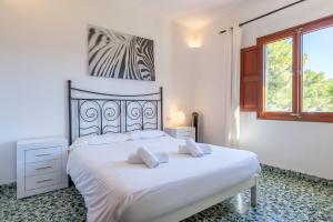 a white bedroom with a large bed and a window at Casa Ca'n Munar in Portocolom