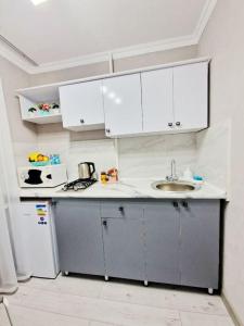 una pequeña cocina con armarios blancos y fregadero en НОВАЯ - 1 комнатная квартира!, en Taraz