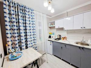 a small kitchen with a table and a sink at НОВАЯ - 1 комнатная квартира! in Taraz