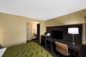 a hotel room with a bed and a desk with a television at Quality Inn SeaTac Airport-Seattle in SeaTac