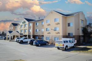 ein großes Gebäude mit Autos auf einem Parkplatz in der Unterkunft Wingate by Wyndham Great Falls in Great Falls