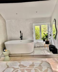 a white bathroom with a tub and a window at The Bothy - A secluded and romantic rural retreat in Llanddyfnan