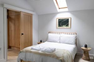 a bedroom with a bed with white sheets and a skylight at The Bothy - A secluded and romantic rural retreat in Llanddyfnan