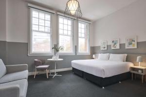 ein Schlafzimmer mit einem Bett, einem Stuhl und einem Sofa in der Unterkunft The Ultimo in Sydney