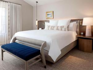 a large white bed with a blue bench in a room at Fairmont Scottsdale Princess in Scottsdale