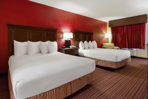 Una habitación de hotel con dos camas y una pared roja. en Quality Inn & Suites, en West Helena