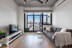 a living room with a couch and a tv at Lovely 2 bedroom apt with views to South Yarra - 03178 in Melbourne