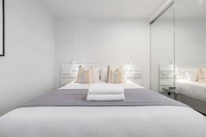 a white bedroom with a large white bed with pillows at Lovely 2 bedroom apt with views to South Yarra - 03178 in Melbourne