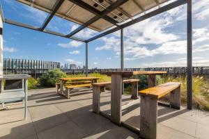 a picnic table and benches under a pergola at Lovely 2 bedroom apt with views to South Yarra - 03178 in Melbourne