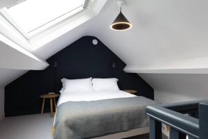 a bedroom with a black and white bed and a window at A Beautiful 3 Bedroom 17th Century Stone cottage in Llanddyfnan
