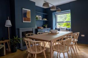 een eetkamer met blauwe muren en een tafel en stoelen bij A Beautiful 3 Bedroom 17th Century Stone cottage in Llanddyfnan