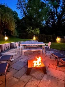 een vuurplaats in een patio met een tafel en stoelen bij A Beautiful 3 Bedroom 17th Century Stone cottage in Llanddyfnan