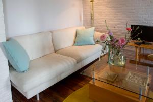 um sofá branco numa sala de estar com uma mesa de vidro em Les Greniers de Madelgaire em Soignies