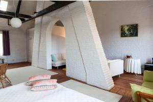 Habitación con pared de ladrillo blanco y cama con almohadas. en Les Greniers de Madelgaire en Soignies