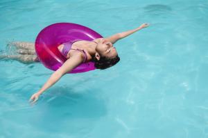 a young girl swimming in a pool with a pink float at Unlock Waters Edge in Dubai