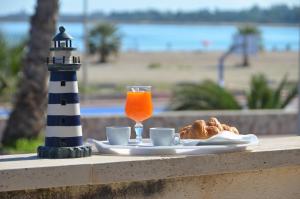 a table with a glass of orange juice and a lighthouse at Villa Faro B&B in San Vito lo Capo