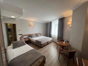 イスタンブールにあるFuar Hotelのベッド2台とテーブルが備わるホテルルームです。