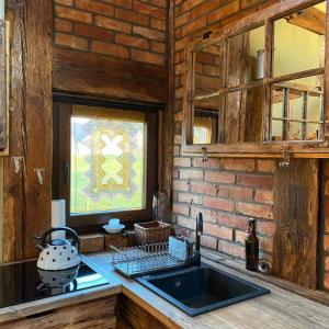 - une cuisine avec un évier et un mur en briques dans l'établissement Ptasia Osada, à Gardna Wielka