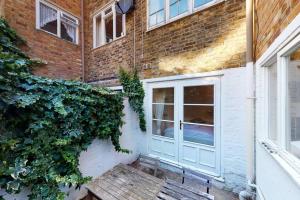 um edifício de tijolos com uma porta branca e hera em Cosy 2 bedroom Garden Flat in West Kensington em Londres