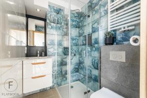 a bathroom with a shower with blue tiles at Flatbook Apartamenty - Jantar Bursztynowe Osiedle in Jantar