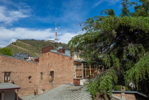 an old brick building with a tv tower on a hill at Barnaba Apartment in Tbilisi City