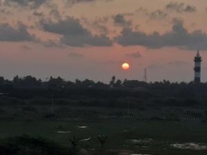 a sunset with a lighthouse and a light house at Holi-Wood Guesthouse in Pondicherry