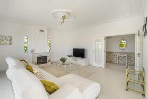 Biały salon z białą kanapą i telewizorem w obiekcie Villa Marina - Pool & Sea View w Albufeirze