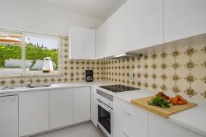 kuchnia z białymi szafkami i deską tnącą w obiekcie Villa Marina - Pool & Sea View w Albufeirze