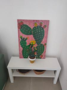 een witte tafel met een schilderij van een cactus bij La casetta del Fico d'India in Marsala