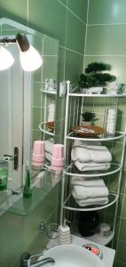 La salle de bains est pourvue d'un lavabo et d'une étagère avec des serviettes. dans l'établissement Apartman Studio DIAMOND, à Subotica