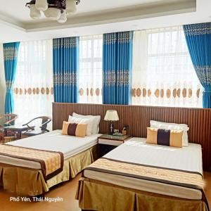 2 camas en una habitación con cortinas azules en Nhu Loan Hotel Pho Yen, en Phố Cò