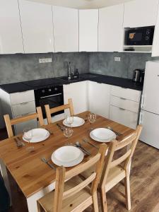 una cocina con una mesa de madera con platos y copas de vino en Apartmán OLOMOUC - SAMOTIŠKY, en Samotíšky