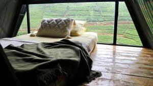 uma cama num quarto com uma grande janela em The ZenDen-Cozy Cabin Perfect For Couples em Lindula