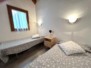 2 camas individuales en una habitación con ventana en Dúplex lluminós a Esterri d'Àneu by RURAL D'ÀNEU en Esterri d'Àneu