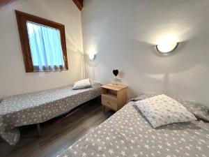 two twin beds in a room with a window at Dúplex lluminós a Esterri d'Àneu by RURAL D'ÀNEU in Esterri d'Àneu