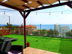 a patio with a lawn and a view of the ocean at Salonikiou Beach Apartments in Agios Nikolaos