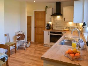 a kitchen with a sink and a counter with oranges on it at Low Chibburn Farm Cottage in Hadston