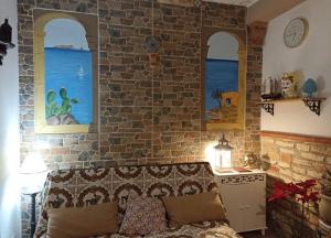 eine Backsteinwand mit zwei Fenstern und einem Sofa in einem Zimmer in der Unterkunft Torre Vallelunga in Trabia