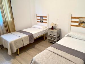 a bedroom with two beds and a dresser with a lamp at Tierra de Mar VYBdenia in Denia