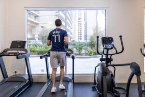 a man standing on a treadmill in a gym looking out the window at Unlock Metropolis Business Bay in Dubai