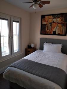 a bedroom with a bed with a ceiling fan and two windows at The Overlook Bed and Breakfast in Glastonbury