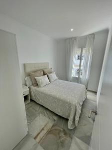 um quarto branco com uma cama e uma janela em apartamentos la reina em Arcos de la Frontera