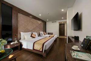a bedroom with a large bed and a living room at Halios Luxury Halong Hotel in Ha Long