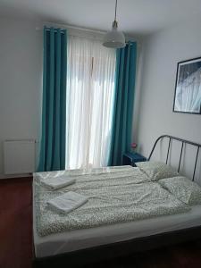 a bedroom with a bed with green curtains and a window at Platan 3 in Świnoujście