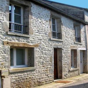 un antiguo edificio de piedra con ventanas y una puerta en The Heart of Sainte Mere Eglise, en Sainte-Mère-Église