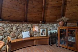 pared de piedra en una habitación con banco de madera en La Pinnetta With Pool - Happy Rentals, en Codrongianos