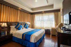 ein Hotelzimmer mit einem großen Bett und einem Schreibtisch in der Unterkunft Shangrila Blu Hotel in Kathmandu