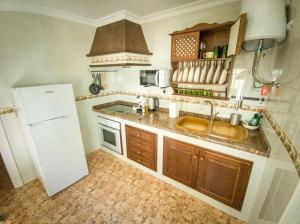a kitchen with a sink and a white refrigerator at La Tienda de Miguel in El Chorro +15 photos
