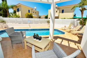 a patio with chairs and a table and a swimming pool at Lindos Villa Ekaterina in Paralimni