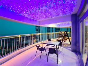 a balcony with a table and chairs and purple lights at Fancy Apartment in Suizhong
